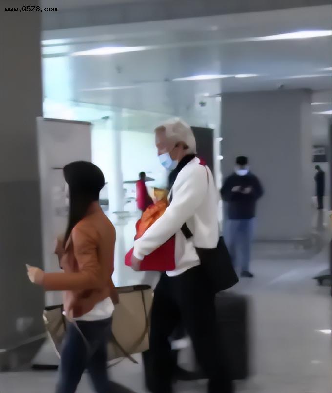 张庭夫妇现身机场，打扮低调躲镜头，怀中的红袋子引人注目