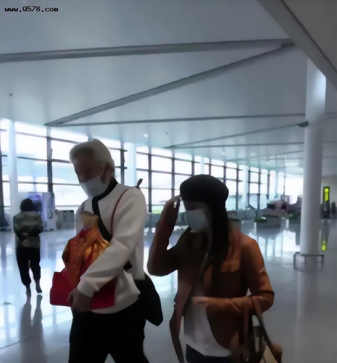 张庭夫妇现身机场，打扮低调躲镜头，怀中的红袋子引人注目